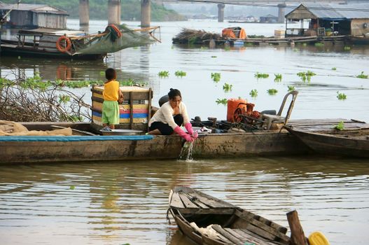 LA NGA, VIET NAM- SEPTEMBER 6: Life at La Nga fishing village, every houseboat is a family, woman wash clothes on river in La Nga, VietNam on September 6, 2013