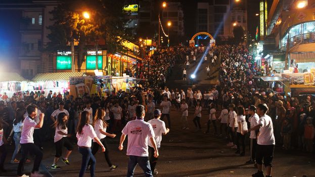 DA LAT, VIET NAM- DEC 29- Lifestyle of young people, they dance with team at outdoor night to celebrate New Year at Flower festival, large audience cheer under limelight, Dalat, Vietnam, Dec 29, 2013