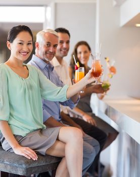 Portrait of happy people with cocktail glasses sitting at the bar counter