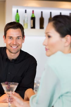 Portrait of a smiling bartender with a woman at the bar counter