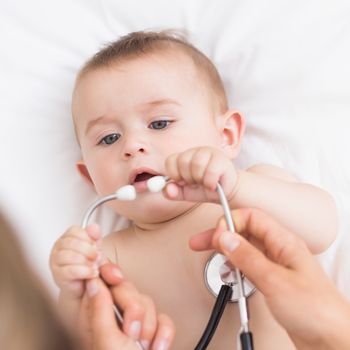 High angle view of adorable baby playing with stethoscope in hospital