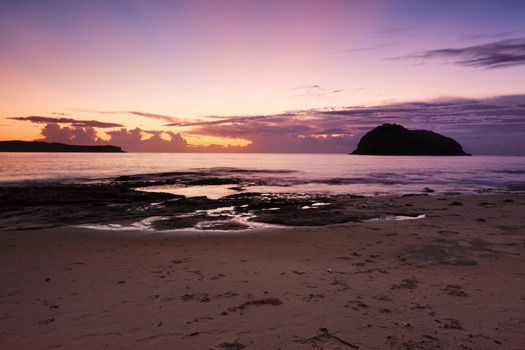 Silhouette view to Lion Island and Box Head at dawn, with the first rays of sunlight reaching up to the sky from behind the clouds, and under the horizon as the sun had not yet risen.