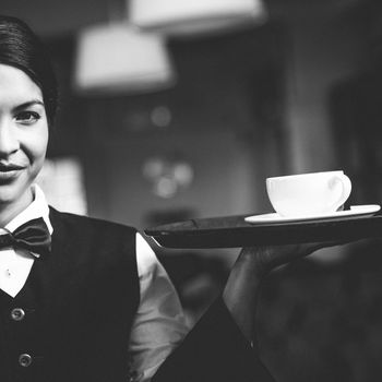 Pretty waitress holding a tray with a cup in a fancy restaurant