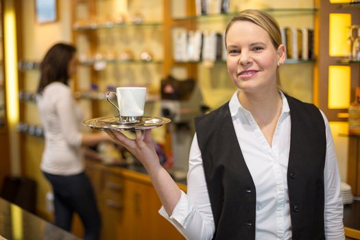 waitress presenting cup of coffee or tea on tray