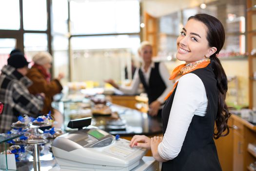 Saleswoman working at cash register or checkout counter in shop
