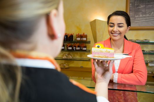 waitress serving cake to customer in cafe or bakery
