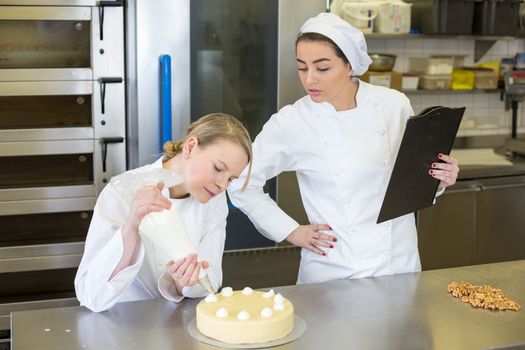 instructor in bakery teaching apprentice how to make cake