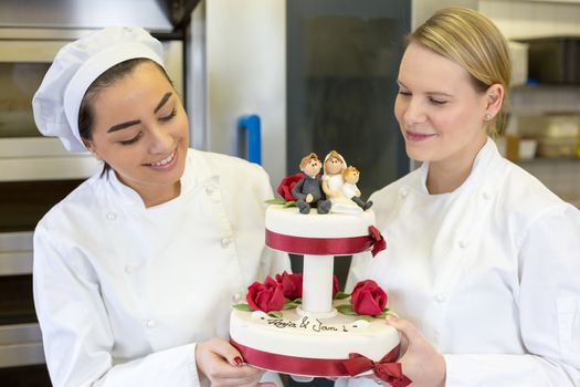 Confectioners or bakers presenting wedding cake in bakery