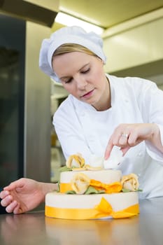 confectioner, baker or pastry cook preparing cake in bakery