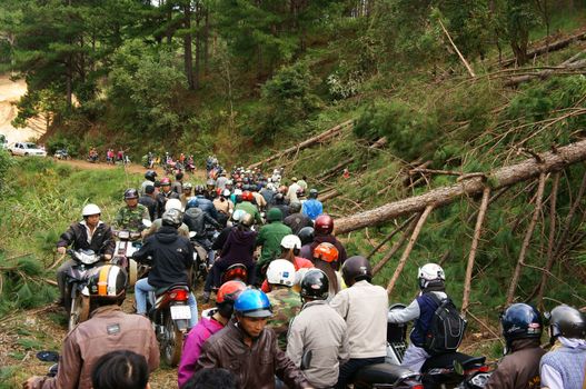 LAM DONG, VIET NAM- NOVEMBER 28: Crowd of people wear helmets ride motorbike wait on mountain pass because traffic jam, cause is pine tree collapsed across the road in Lam Dong, VietNam, Nov 28, 2013