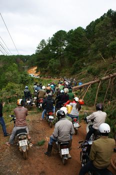 LAM DONG, VIET NAM- NOVEMBER 28: Crowd of people wear helmets ride motorbike wait on mountain pass because traffic jam, cause is pine tree collapsed across the road in Lam Dong, VietNam, Nov 28, 2013