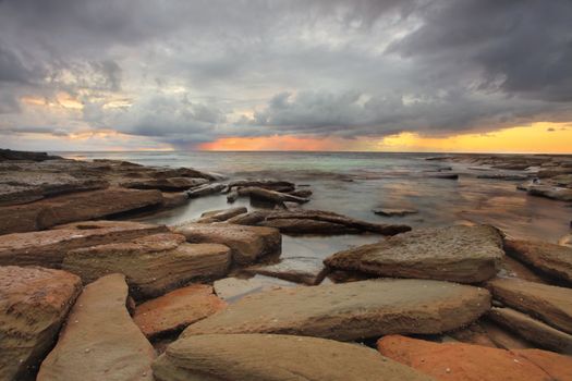 The sun rays burst out of the clouds.   The oxidised iron in some of the foreground rocks almost match its colours.