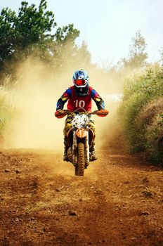 The motorcycle race hole on December at Dambri waterfall, motorcyclist try to speed up goal, red soil way, indistinct dust