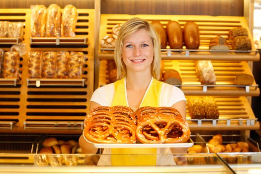 Shopkeeper in Bakery or baker's shop present a tablet full of pretzels