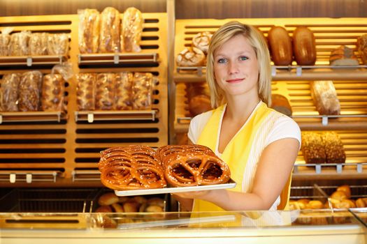 Shopkeeper in Bakery or baker's shop present a tablet full of pretzels