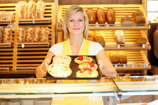 Shopkeeper in bakery presents a tablet full of cakes