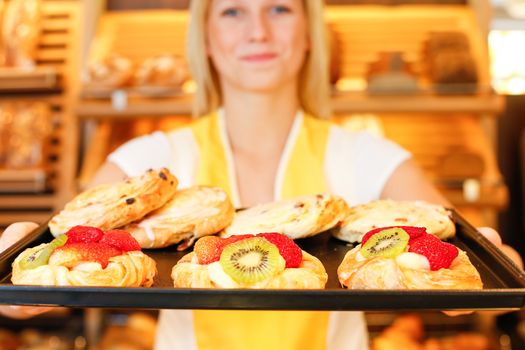 Bakery shopkeeper presents pastry and cakes
