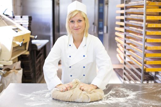 Baker kneading dough in a bakehouse or bakery