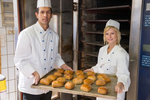 Two bakers with tablet of buns in a bakery
