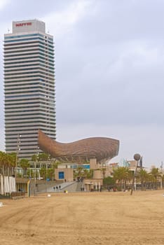 Barcelona, Spain - January 25, 2014:   Gehry's Sphere Sculpture, and Fish sculpture in Port Olympic in Barcelona, Spain as viewed from the beach on early afternoon January 25, 2014