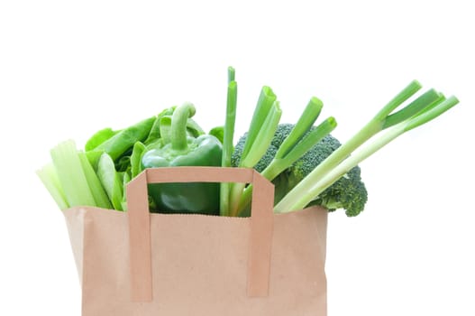 Brown paper bag with healthy green vegetables over a white background 