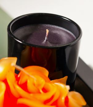 Black candle near a rose decoration, white background