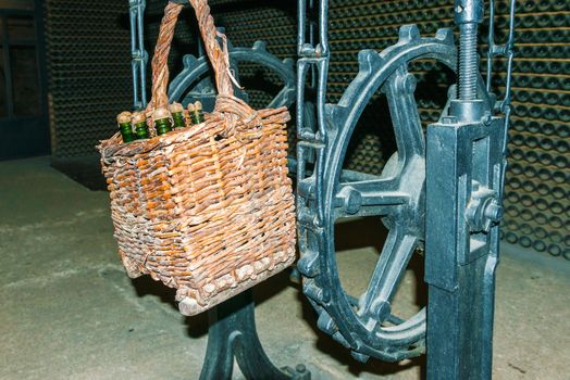 Wine bottles in the basket and the bottles at the background. Codorniu winery is located in Sant Sadurni d'Anoia near Barcelona, Spain. The first known document states that the winery is dating to beginning of sixteen century.