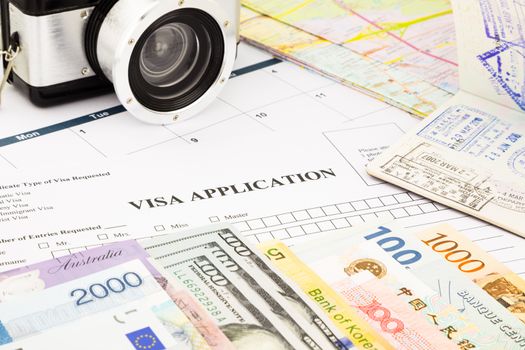 closeup visa application form, passport, camera and world currency. planning schedule for holiday and vacation