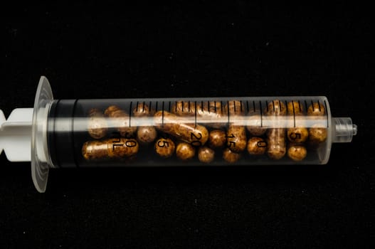 Medical Syringe Full of Pill Drugs on a Black Background