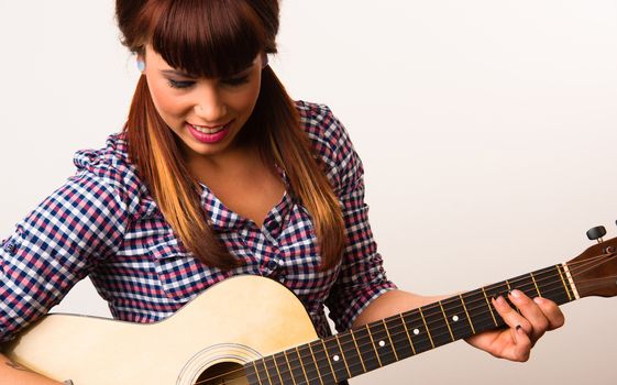 Beautiful redhead plays acoustic guitar in plaid