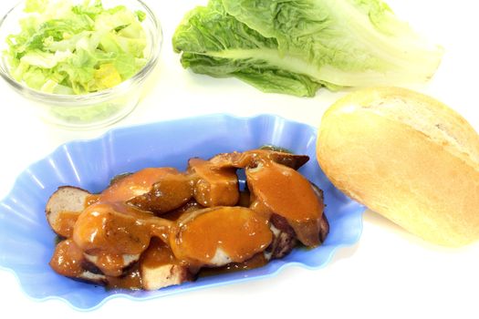 Currywurst with salad in a bowl on a light background