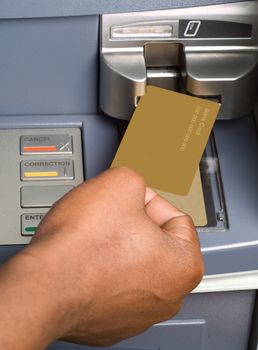 South African or African American drawing cash money with bank ATM card in auto teller machine
