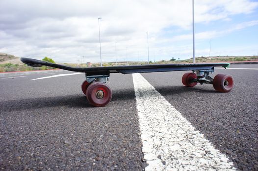 Vintage Style Longboard Black Skateboard on an Empty Asphalt Desert Road