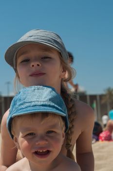 Brother and sister in denim caps on the beach