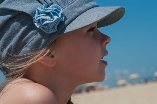 Lovely little girl in denim cap on the beach
