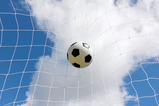 Soccer ball in net on blue sky background
