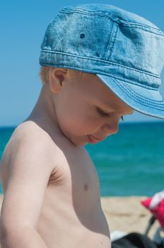 Little boy in denim cap on the beach