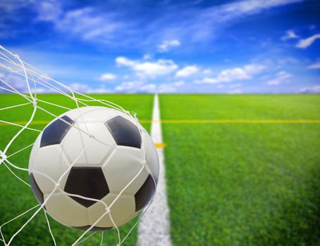 soccer ball in goal net over blue sky background