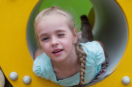 Young girl lying in crawl tube on the playground