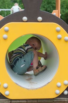 Young boy sitting in crawl tube on the playground