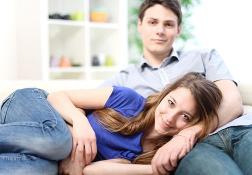 Attractive woman lengthened on the thighs of her boyfriend on a sofa in living-room
