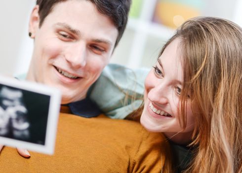 Beautiful couple watching with emotion ultrasound pictures of their baby