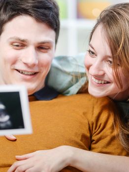 Beautiful couple watching with emotion ultrasound pictures of their baby