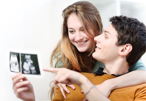 Beautiful couple watching with emotion ultrasound pictures of their baby