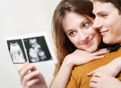 Beautiful couple watching with emotion ultrasound pictures of their baby