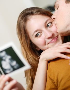 Beautiful couple watching with emotion ultrasound pictures of their baby