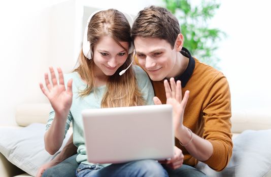 Happy young couple talking through the computer with video chat