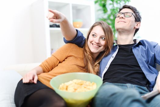 Couple enjoying watching a movie at home laughing on the couch