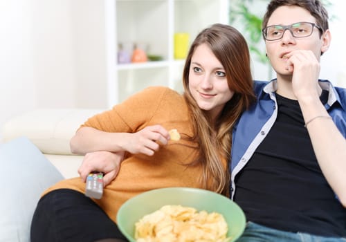 Pretty lovers watching for television on a sofa at studio apartment