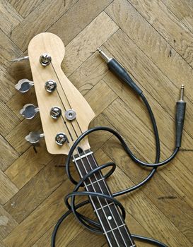 electric bass and audio cable on wood background